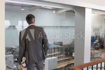 Male engineer with blueprints watching factory floor