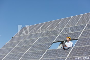Male engineer with digital tablet examining sunny solar panels
