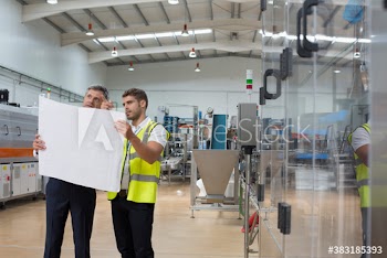 Male engineers with blueprints in factory