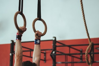 Male Gymnast Holding On To Two Wooden Rings