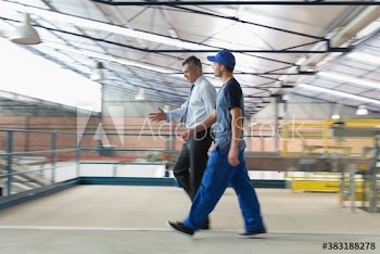 Male manager and worker walking in factory