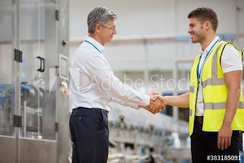 Male manager shaking hands with worker in factory