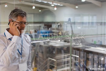 Male manager talking on smart phone above factory floor