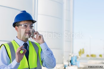 Male manager talking on smart phone below storage tanks