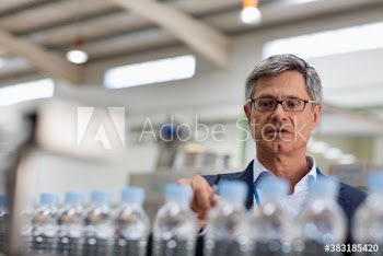 Male manager watching water bottles on factory production line