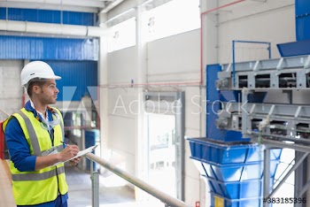 Male manager with clipboard supervising recycling plant