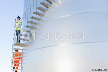 Male manager with walkie talkie on storage tank stairs
