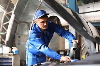Male mechanic refilling car oil in service center