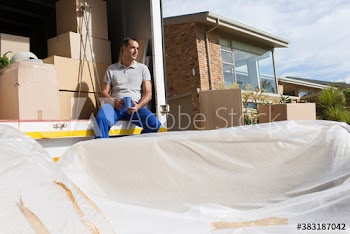 Male mover with coffee taking a break at back of sunny moving van