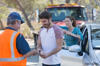 Male roadside mechanic helping couple with car breakdown at roadside