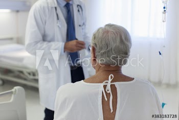Male senior patient listening to doctor in hospital room