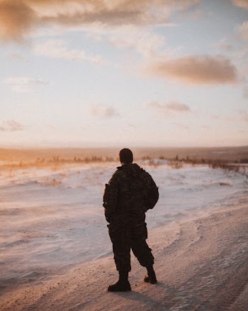 male soldier standing on sand dunes