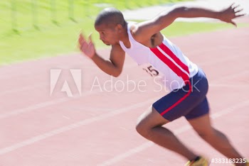 Male sprinter athlete running on sunny running track