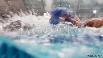 Male swimmer splashing in swimming pool