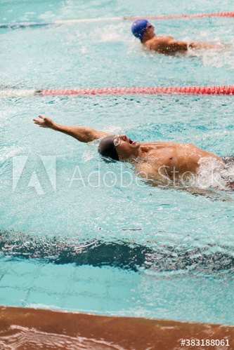Male swimmers doing backstroke in swimming pool