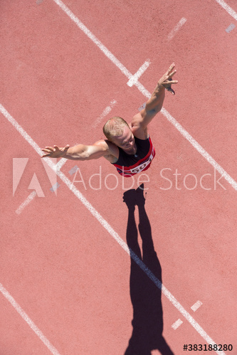 Male track and field athlete jumping on sunny running track