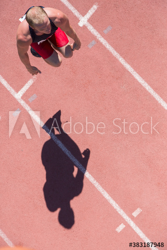 Male track and field athlete preparing on sunny running track