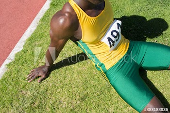 Male track and field athlete resting in sunny grass