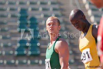 Male track and field athletes on sunny running track