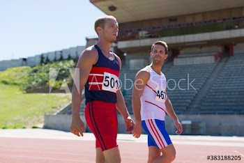 Male track and field athletes on sunny running track