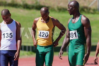 Male track and field athletes on sunny running track
