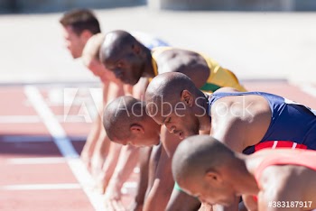 Male track and field athletes ready at sunny starting line