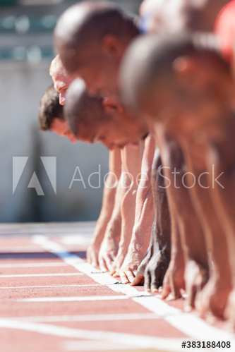 Male track and field sprinters ready at sunny starting line