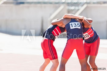 Male track and field team in huddle on sunny running track