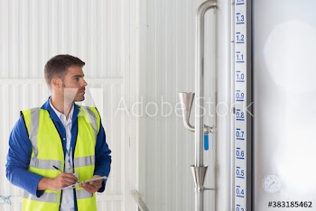 Male worker examining factory storage tank