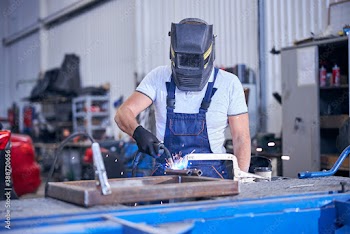 Male worker in welding helmet welding metal in garage