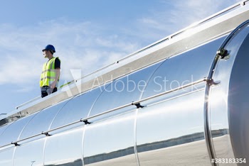 Male worker looking away on top of sunny milk tanker