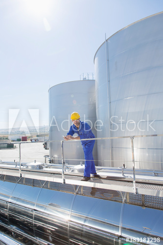 Male worker on milk tanker on sunny dairy farm