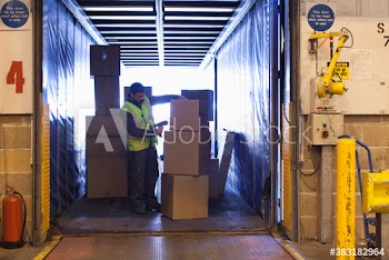 Male worker scanning boxes in truck at warehouse loading dock