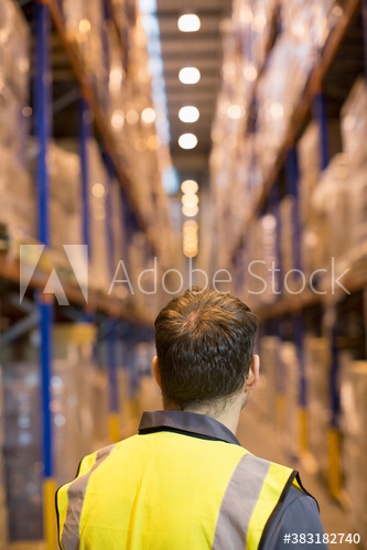 Male worker standing in aisle of distribution warehouse