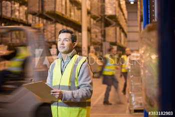 Male worker with clipboard in distribution warehouse