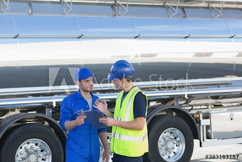 Male workers talking outside milk tanker
