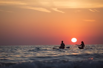 Man and Woman Boat Rowing in Sea during Golden Hour