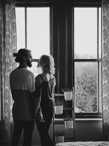 man and woman facing each other near window