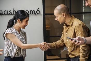 Man and Woman Handshaking Near Window