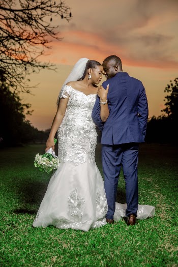 Man and Woman Holding Each Other's Arms While Standing on Grass