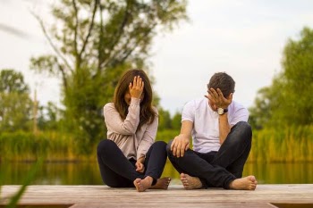 Man and Woman Holding Forehead Sittin on Bridge