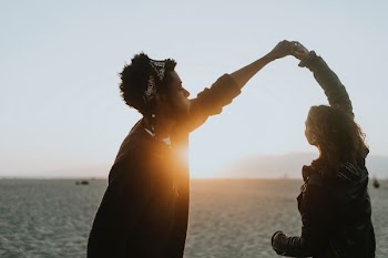 man and woman holding hands beside body of water