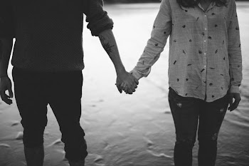 man and woman holding hands standing on body of water