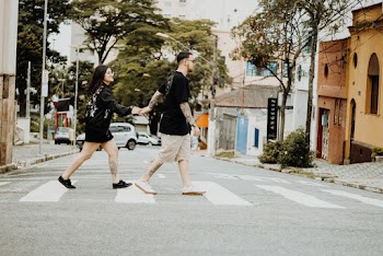 Man and Woman Holding Hands While Crossing on Pedestal Lane