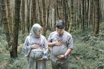 man and woman holding their tummies surrounded by trees