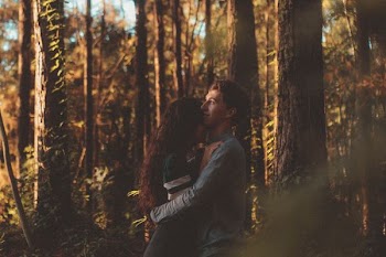 man and woman hugging each other on forest
