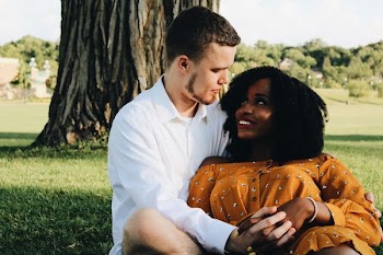 man and woman hugging while sitting on lawn grass