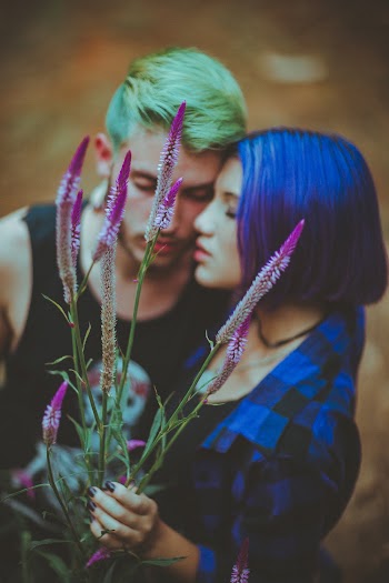 Man and Woman Hugging While Woman Holding Purple Flowers