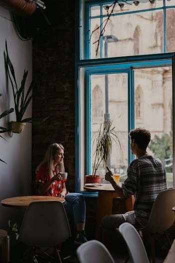 man and woman in front of round brown wooden pedestal table