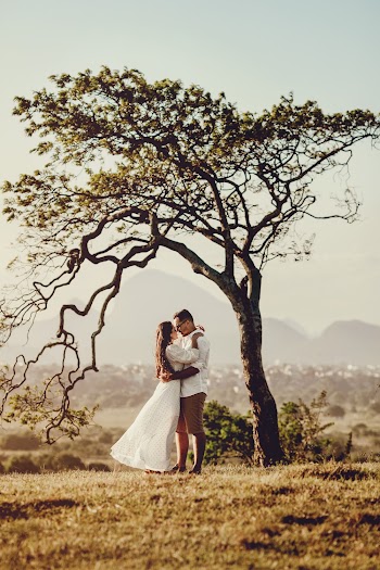 Man and Woman in Holding Each other Standing Beside Tree